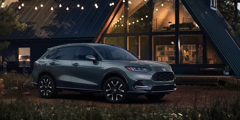 2027 Honda HR-V EX-L in Nordic Forest Pearl three quarter view parked in front of a cabin (Subcompact Crossover SUV).