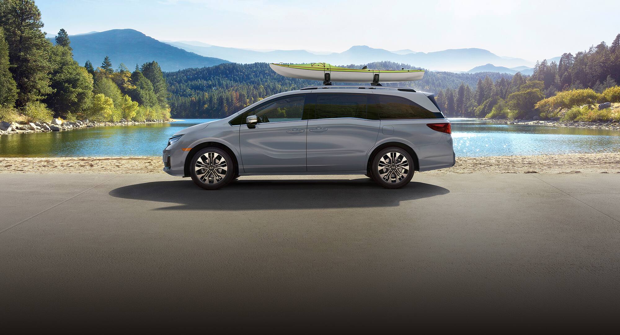 2027 Honda Odyssey Elite in Sonic Gray Pearl profile parked by a lake with a kayak on the roof (Minivan).