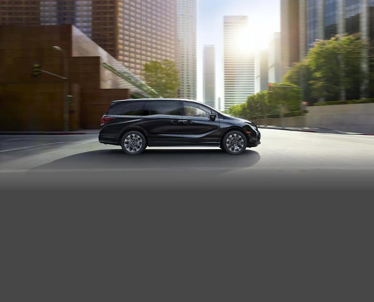 2027 Honda Odyssey Elite driving through city environment.